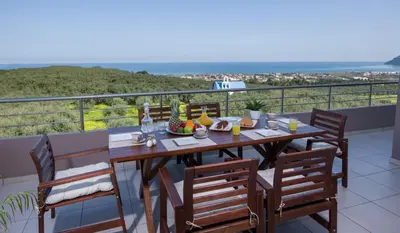 a table with food on top of a balcony at Villa Elisabeth View in Plataniás