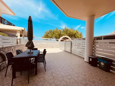 a patio with a table and chairs and an umbrella at Alcyone Apartment in Kissamos