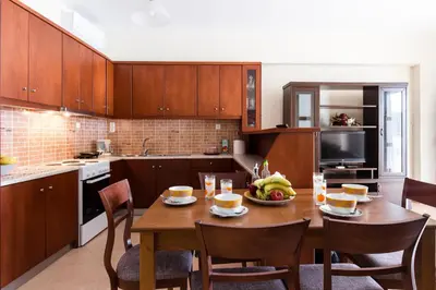 a kitchen with a wooden table and some chairs at Alcyone Apartment in Kissamos