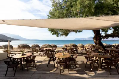 a group of tables and chairs on the beach at Alcyone Apartment in Kissamos
