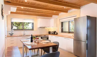 a kitchen with a table and a stainless steel refrigerator at Orientem Villa Heated Pool in Georgioupoli