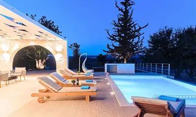 a swimming pool with lounge chairs next to a swimming pool at Orientem Villa Heated Pool in Georgioupoli