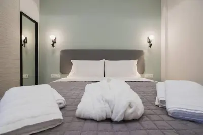 a bedroom with a bed with white sheets and pillows at Peris 5 with Yard steps to Bus St & Old Town in Chania Town