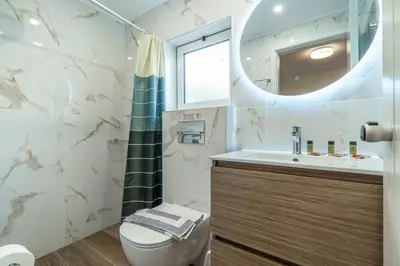 a bathroom with a toilet and a sink and a mirror at Rhoe Seaside Apartments in Agia Marina Nea Kydonias