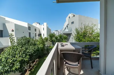 a balcony with two chairs and a table at Rhoe Seaside Apartments in Agia Marina Nea Kydonias
