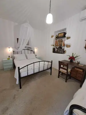 a bedroom with a large bed and a table at Olga's traditional stone house, Palaiochora in Kondokiníyion