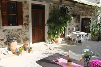 a patio with a table and chairs and a building at Olga's traditional stone house, Palaiochora in Kondokiníyion