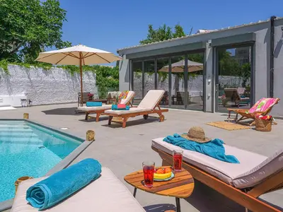 a backyard with a swimming pool with chairs and a swimming pool at Villa Belle Helene Kalamaki Chania in Kalamaki Chanion