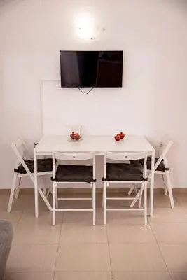 a white table and chairs with a tv on a wall at Nikis Apartment 2 in Chania Town