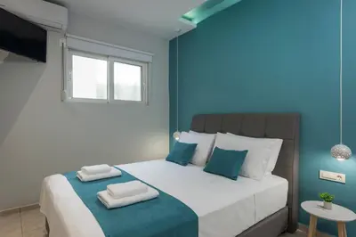 a blue bedroom with a bed with two towels on it at JT Apartments in Kissamos