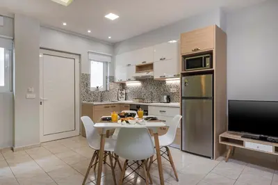 a kitchen with a table and chairs and a refrigerator at JT Apartments in Kissamos