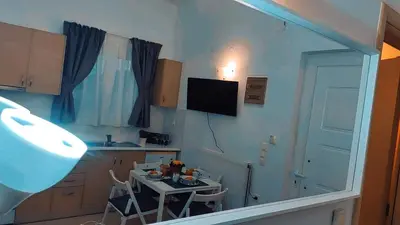 a kitchen with a table with chairs and a television at Nikis Apartment 3 in Chania Town