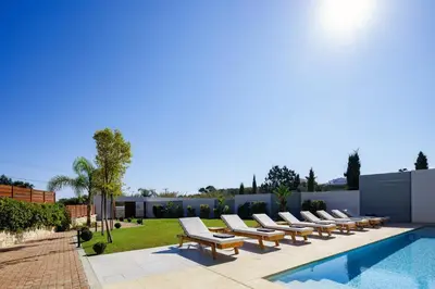 a row of lounge chairs next to a swimming pool at Villa Aroma in Chania Town