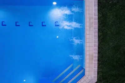 a reflection of a swimming pool in the grass at Villa Golden Hill in Chania Town