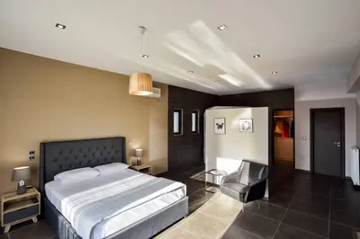 a bedroom with a bed and a chair in it at Adorno Luxury Villa in Chorafakia