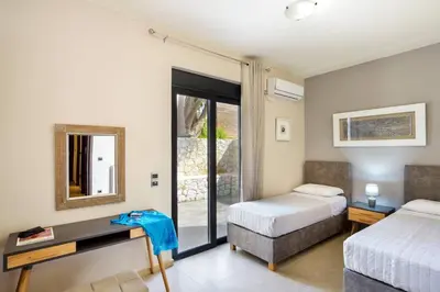 a bedroom with two beds and a desk with a mirror at Adorno Luxury Villa in Chorafakia