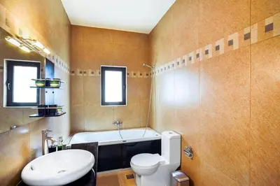 a bathroom with a tub and a toilet and a sink at Adorno Luxury Villa in Chorafakia