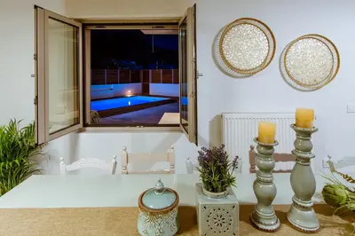 a room with a table and a window with a pool at Chania Paradise Retreat - Falasarna Villa Nostalgia in Plátanos
