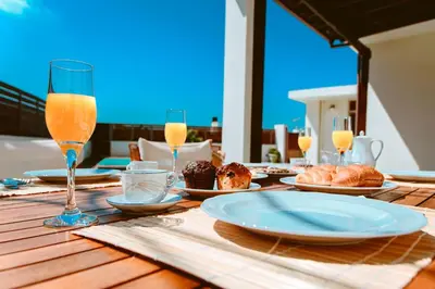 a wooden table with plates of food and glasses of orange juice at Chania Paradise Retreat - Falasarna Villa Nostalgia in Plátanos