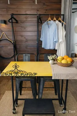 a yellow table with a bowl of fruit and a shirt on a rack at dream tiny house & luxury tent, 6 km from center Chania in Chania Town