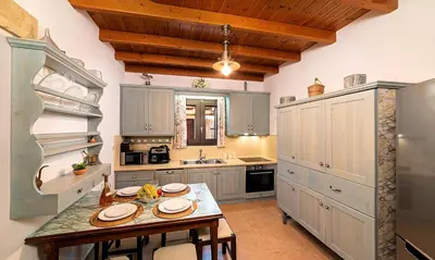 a kitchen with blue cabinets and a table with chairs at Cretan Kera Villa Heated Pool in Kerá