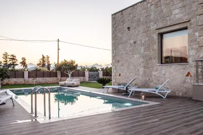 a swimming pool in the backyard of a house at Villa Pervoli in Varípetron