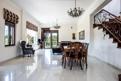 a dining room and living room with a table and chairs at Villa Pervoli in Varípetron
