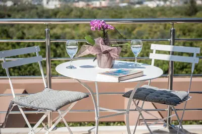a white table with two chairs and a vase with flowers at Villa Pervoli in Varípetron