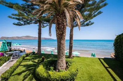 two palm trees in a park next to the beach at Kristall Suites in Stalos