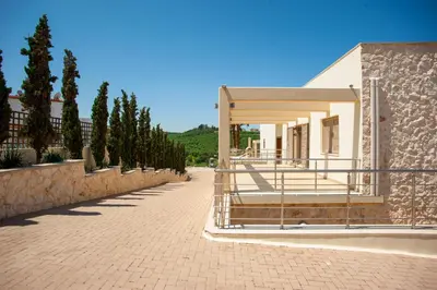 a white building with a stone wall and trees at Luxury 6-Bedroom Villa With Private Pool- Villa Prigipessa in Chania Town