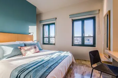 a bedroom with a bed and a desk and windows at House 8 - In the Heart of Venetian town w. Parking in Chania Town