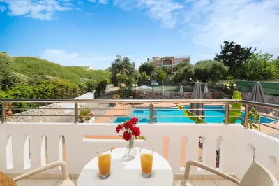 a table with a vase of flowers on a balcony at Aphrodite Apartments in Kalyves