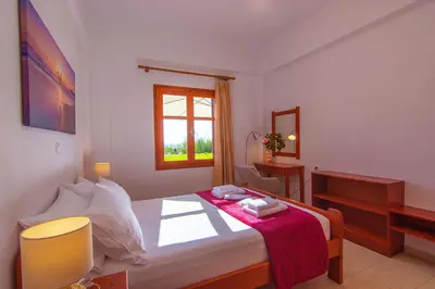 a bedroom with a bed with a red blanket on it at Liviko Beach Apartments - only adults in Frangokastello