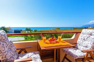 a table with a bowl of fruit and drinks on a balcony at Liviko Beach Apartments - only adults in Frangokastello