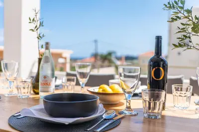 a table with a bowl of fruit and wine bottles at Villa Oliveto in Tavronitis