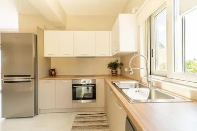 a kitchen with white cabinets and a stainless steel refrigerator at Villa Oliveto in Tavronitis