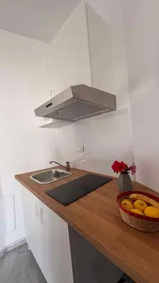 a kitchen with a sink and a bowl of fruit on a counter at Menelaos Apartments in Daratso
