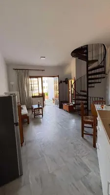 a kitchen with a living room with a spiral staircase at Menelaos Apartments in Daratso