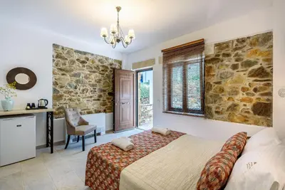 a bedroom with a bed and a stone wall at Minos Country Living Apartments in Agrilés
