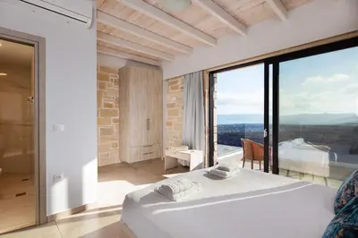 a bedroom with a bed and a large glass window at Argyrie Villas, luxury, amazing sea view, heated pool in Kalleryianá