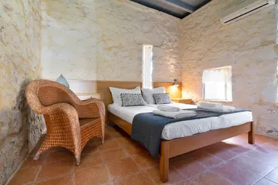 a bedroom with a bed and a wicker chair at Villa Mediterranea - Heated Pool optional in Livadia