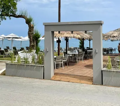 a pavilion with tables and chairs in front of the ocean at Wave rooms in Maleme