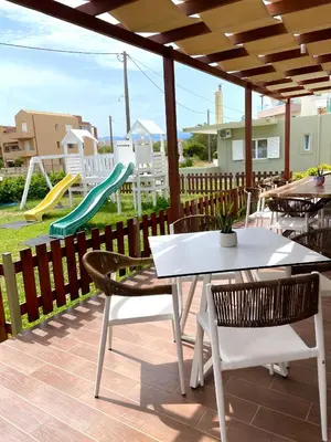 a patio with a table and chairs and a playground at Wave rooms in Maleme