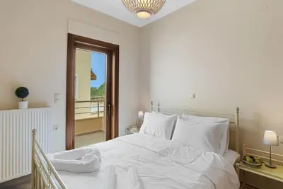 a bedroom with a white bed and a balcony at Amphitrite Beach House in Chania Town