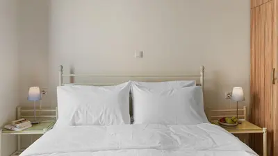 a bed with white sheets and pillows and two lamps at Amphitrite Beach House in Chania Town