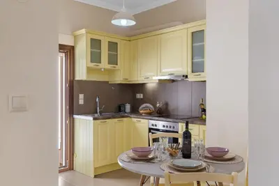 a kitchen with yellow cabinets and a table with wine glasses at Amphitrite Beach House in Chania Town