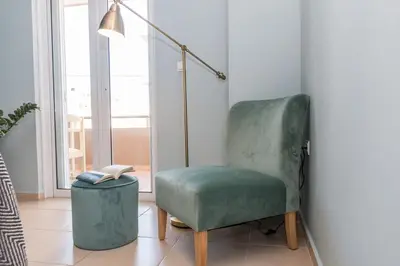 a green chair sitting in a room with a lamp at Elizabeth cozy home close to the beach in Chania Town