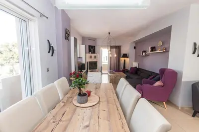 a living room with a wooden table and white chairs at Elizabeth cozy home close to the beach in Chania Town