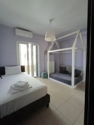 a white bedroom with a bed and a window at Elizabeth cozy home close to the beach in Chania Town