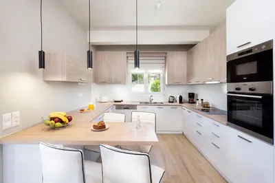 a kitchen with white cabinets and a table and chairs at MM Villa in Chania Town